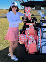 Woman in golf attire standing next to a golf cart with women's lightweight golf cart bags.
