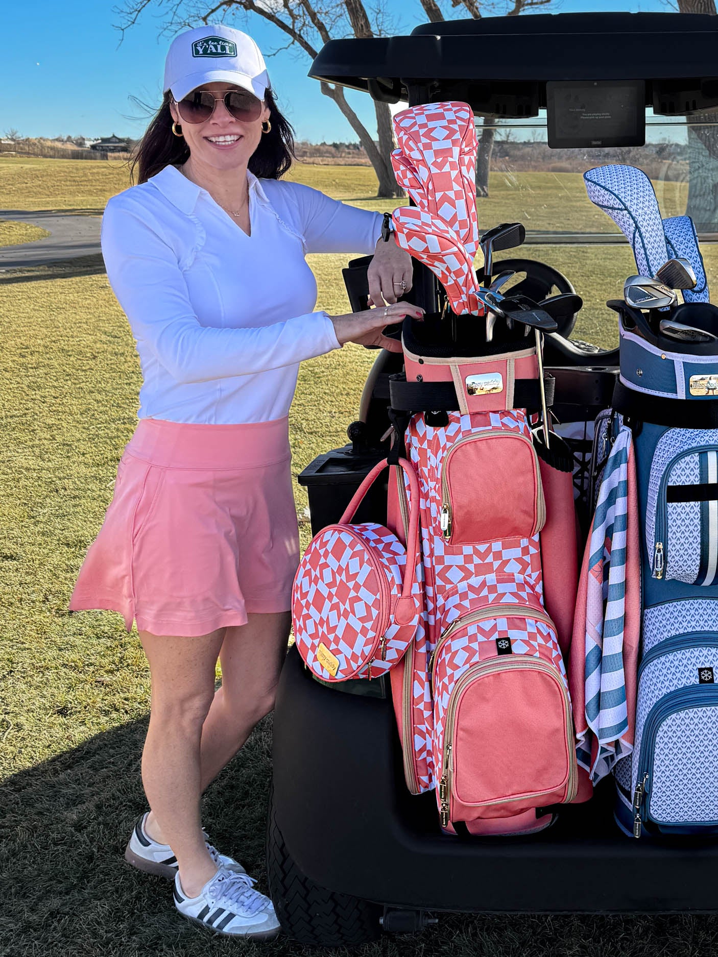 Woman in golf attire standing next to a golf cart with women's lightweight golf cart bags.