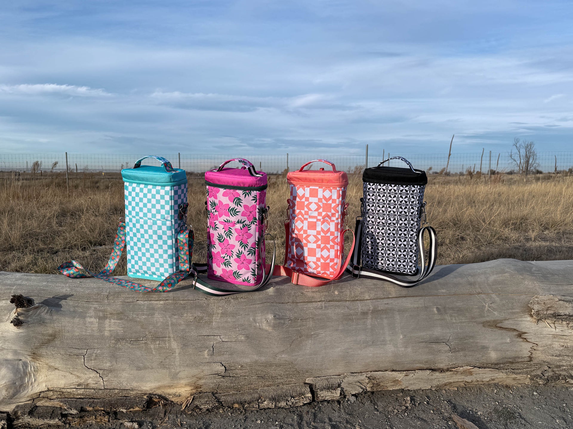 Four colorful coolers on a wooden surface with a natural background