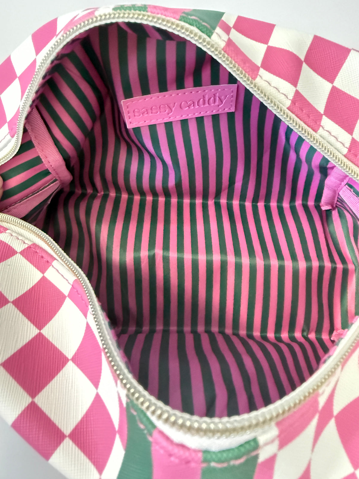 Inside of the pink and white check golf pouch showing the green and pink striped lining
