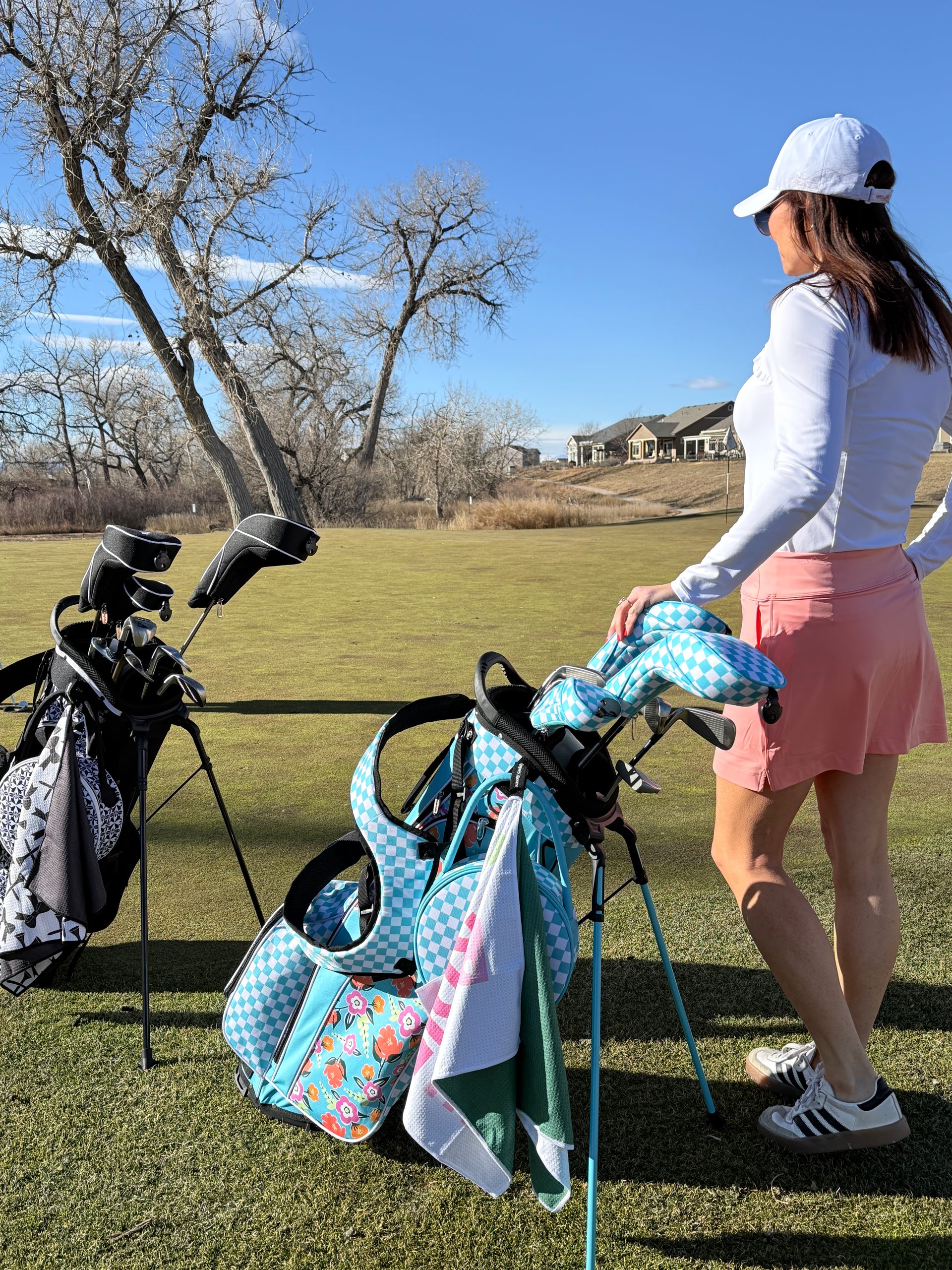 Woman on a golf course with a colorful golf bag and clubs.