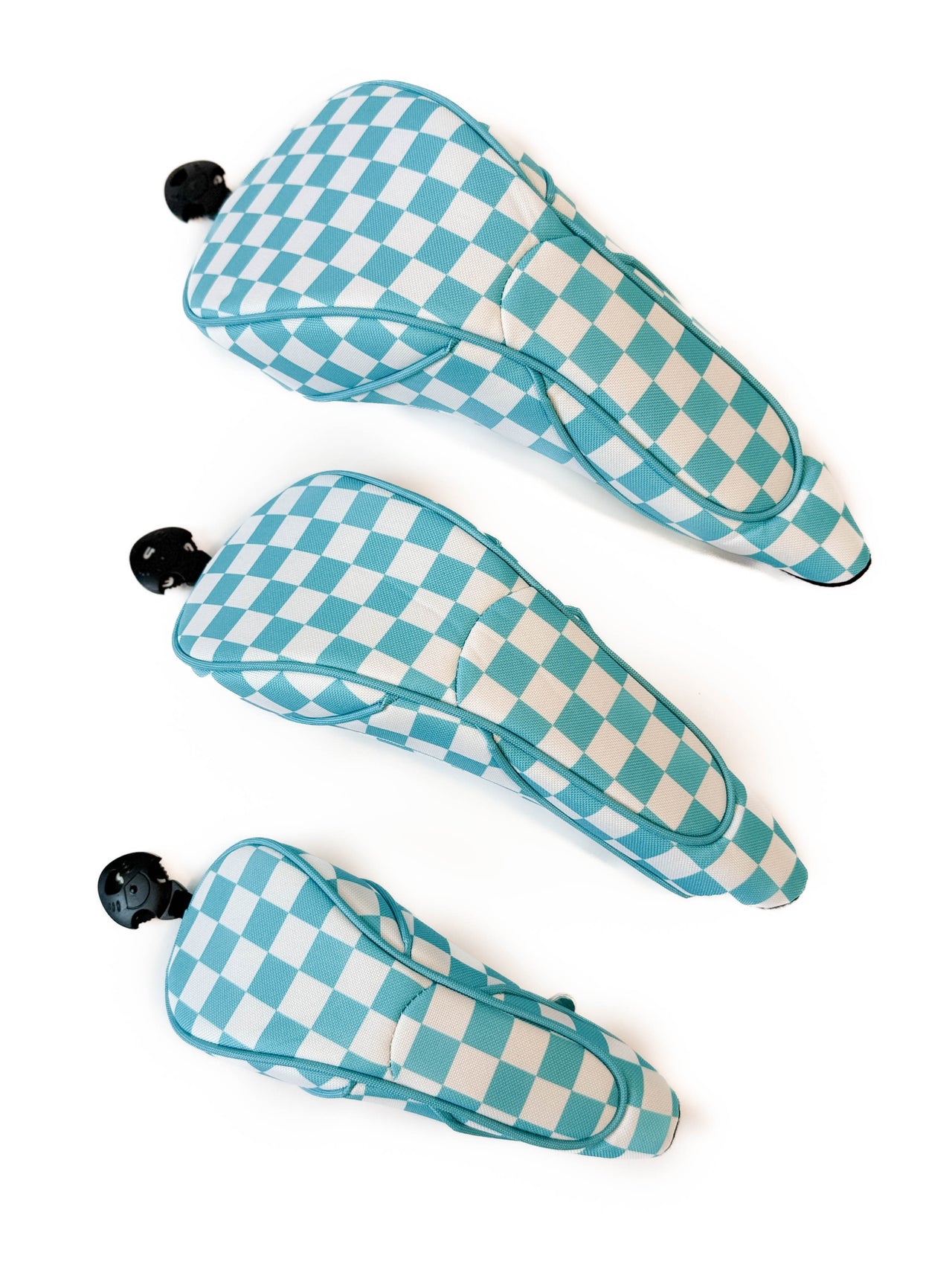 Three turquoise and white checkered golf club head covers on a white background