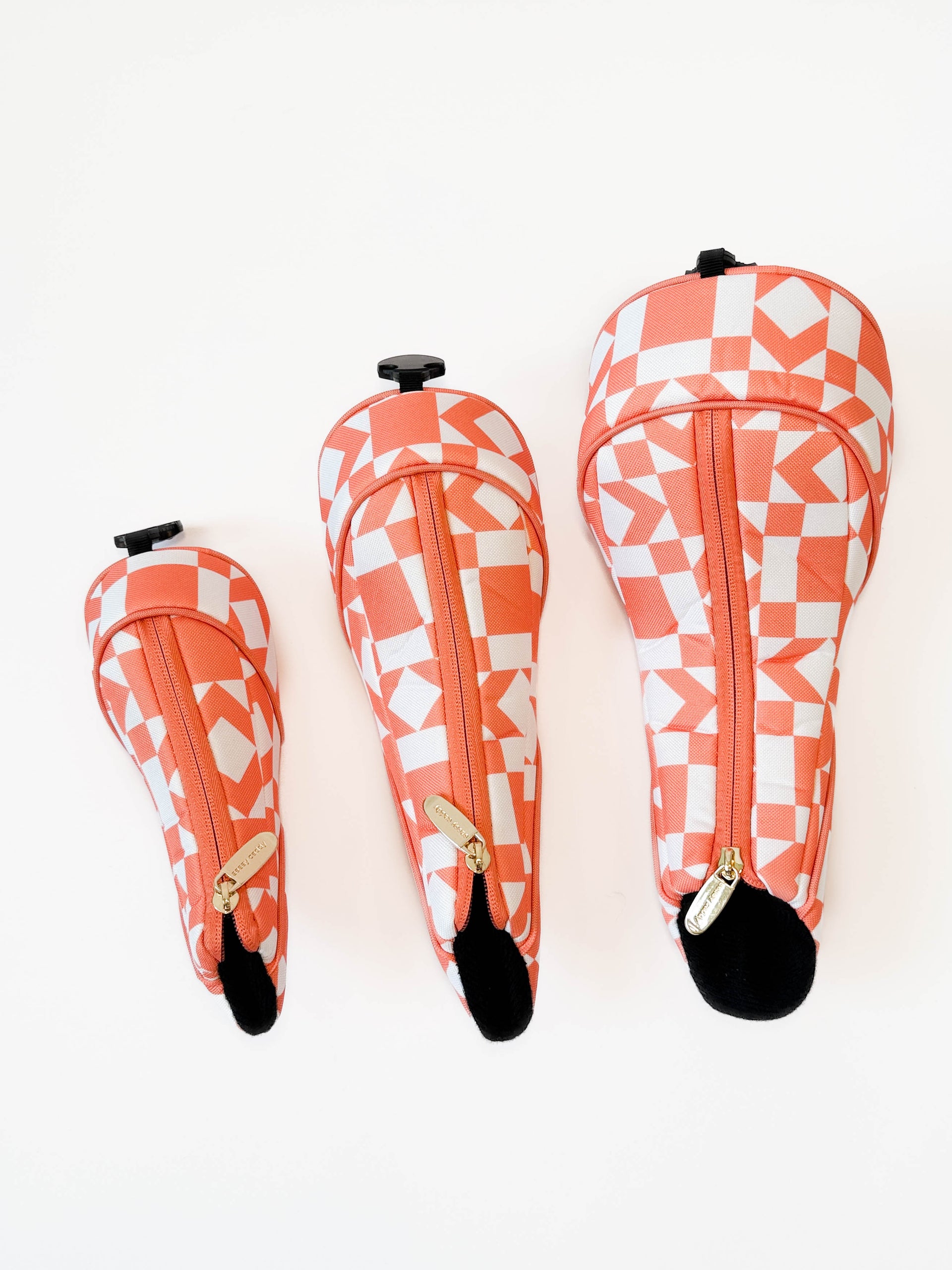 Set of three geometric-patterned golf club headcovers on a white background